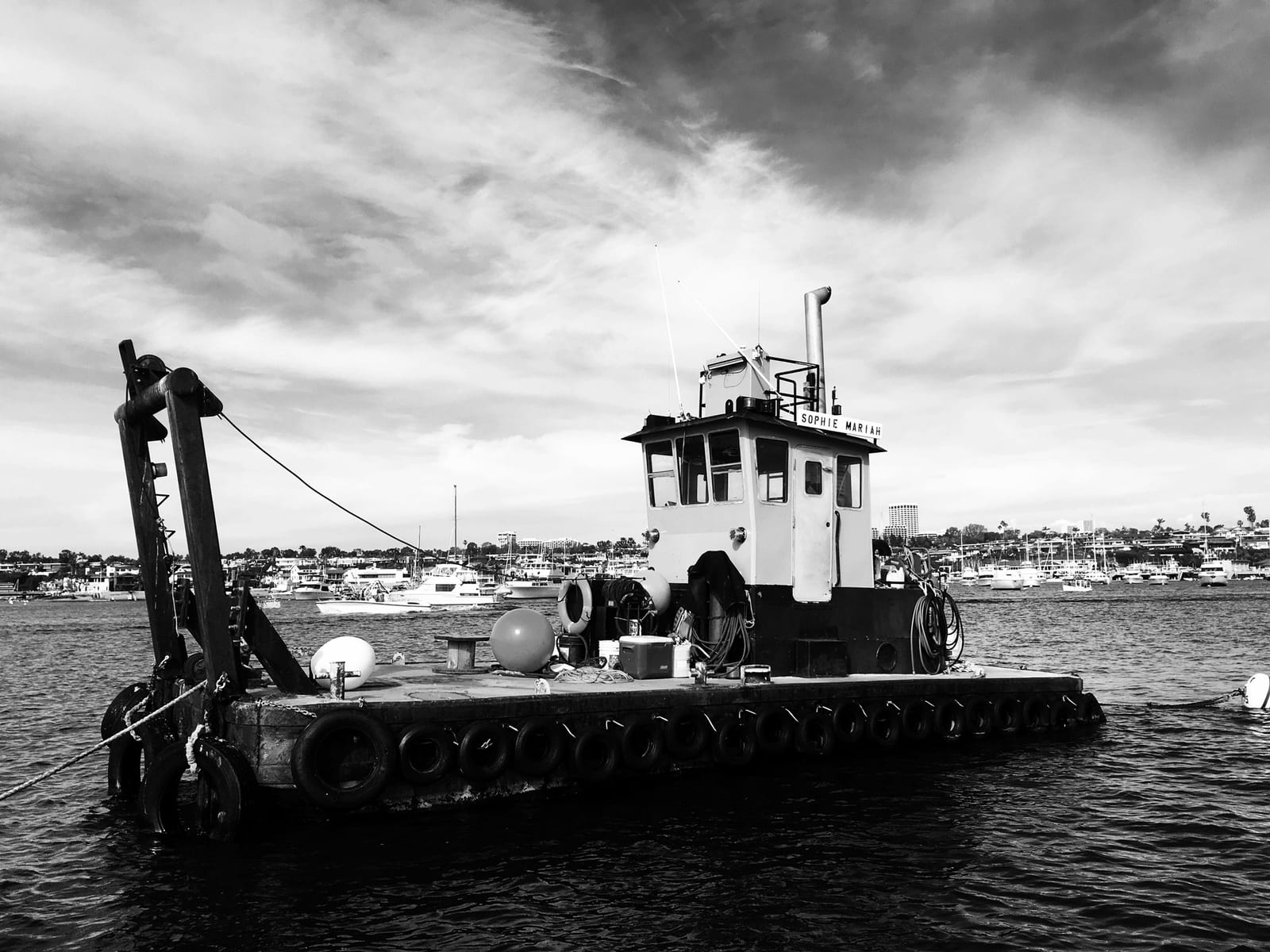 The work barge Sophie Mariah with a crane arm, tyre fenders along the hull, and a pilothouse, moored in open water